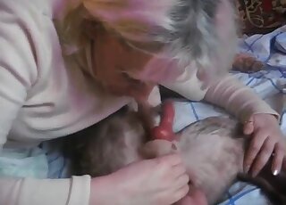 Mature blonde sucks the dog's cock and swallows a bit of sperm